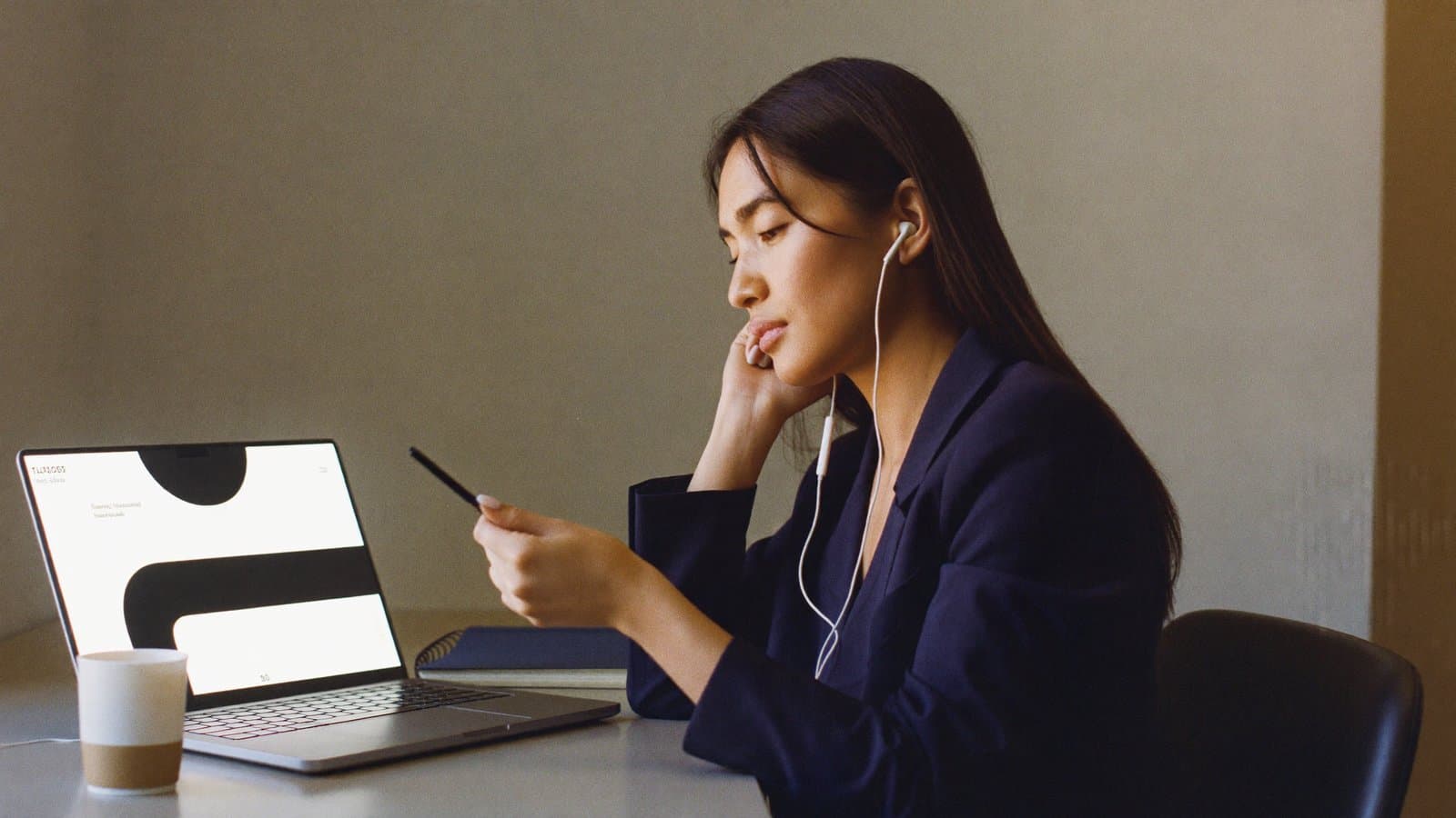 An agent reviewing a roleplay session on a laptop, earbuds in, taking notes
