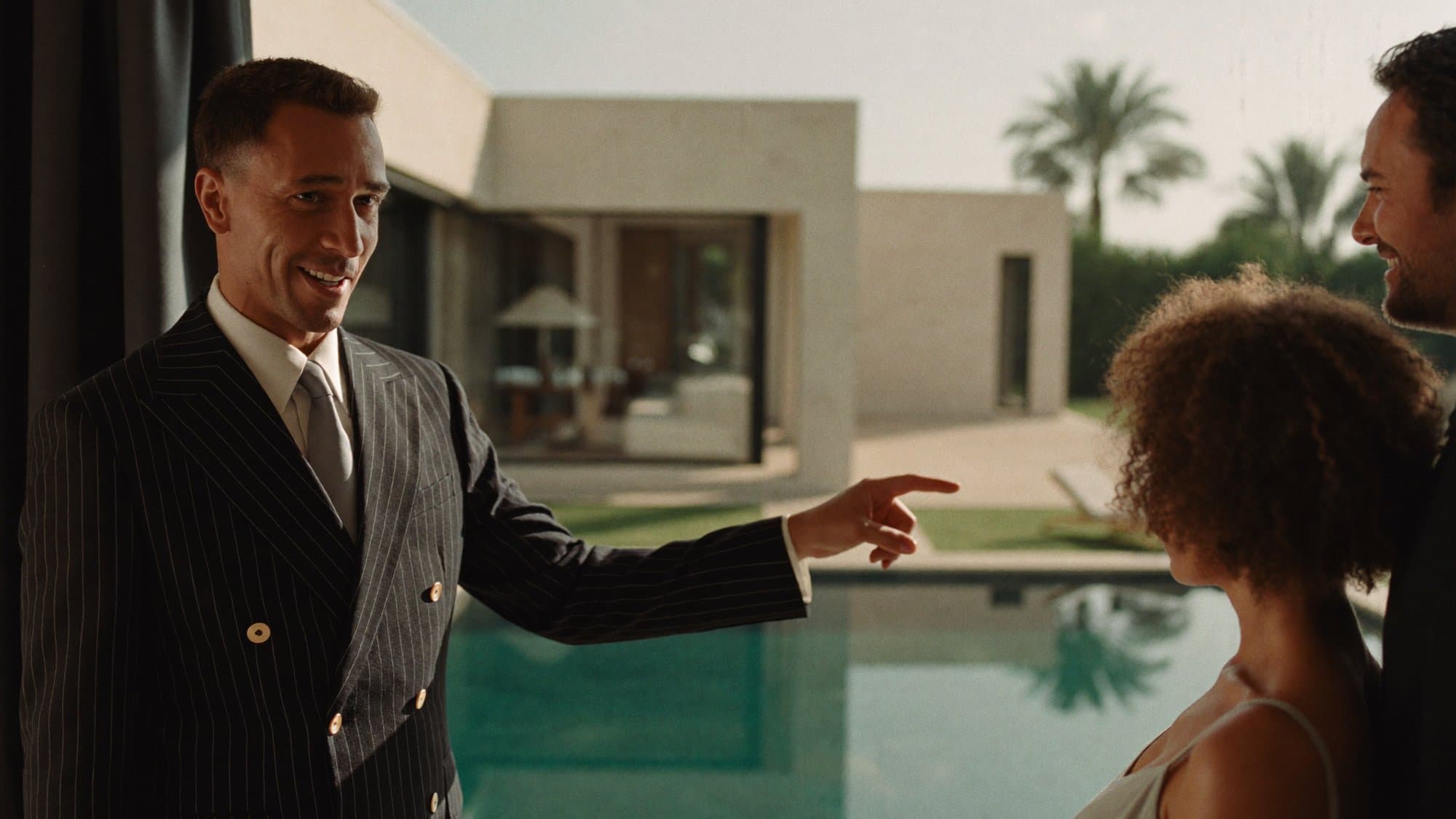 A confident real estate agent mid-conversation with a couple, gesturing toward the view